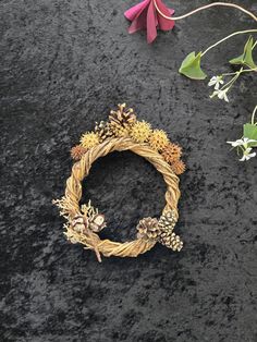 a close up of a wreath on a black surface with flowers and plants around it