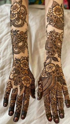 two hands with henna tattoos on them, one is showing the intricate pattern and the other has an elaborate design