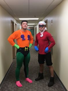 two men dressed in costumes standing next to each other on a hallway with carpeted walls