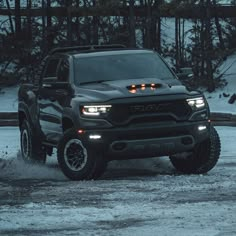 a black truck is driving through the snow