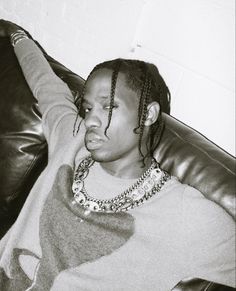 a black and white photo of a young man with dreadlocks sitting on a couch