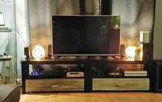 a flat screen tv sitting on top of a wooden entertainment center in a living room