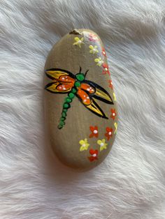 a painted rock with a dragonfly on it