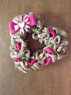 a pink and gray wreath with flowers on it sitting on top of a wooden table