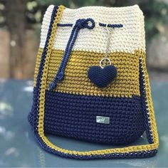 a crocheted bag with a heart hanging from the handle on top of it