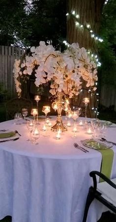 the table is set with white flowers and lit candles for an elegant dinner party or celebration