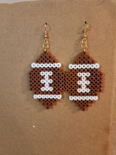 a pair of brown and white beaded earrings with a football design on the front