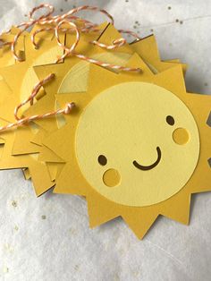 some yellow paper cut outs with a smiling face on them and string attached to it