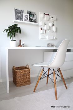 a white chair sitting in front of a desk next to a basket on the floor