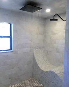 a bathroom with a shower head, window and tile flooring on the walls is shown