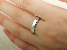 a woman's hand with a wedding ring on her left hand, wearing a white gold band