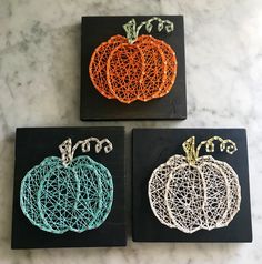 three pieces of string art sitting on top of a marble counter next to each other