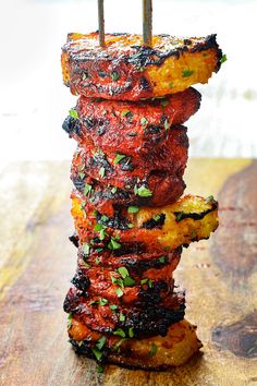 a stack of grilled meat sitting on top of a wooden cutting board