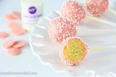 cake pops with white sprinkles on a plate next to confection