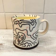 a white and black coffee cup sitting on top of a counter