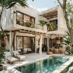 a house with a pool in front of it surrounded by palm trees and greenery