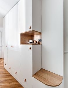 a kitchen with white cabinets and wood flooring next to a wall mounted microwave oven