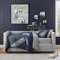 a bedroom with blue walls and a white couch in the foreground, framed pictures on the wall