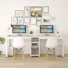 two computers sitting on top of a wooden desk in front of a wall with pictures