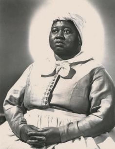 an old black and white photo of a woman in a dress with a turban on her head