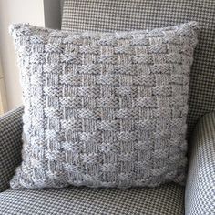 a gray and white pillow sitting on top of a chair