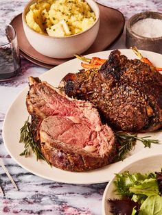 a plate with meat and vegetables on it next to a bowl of mashed potatoes