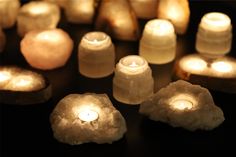 several lit candles sitting on top of a black table next to rocks and stones in the shape of hearts