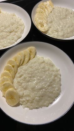 three white plates topped with food on top of a black countertop next to each other