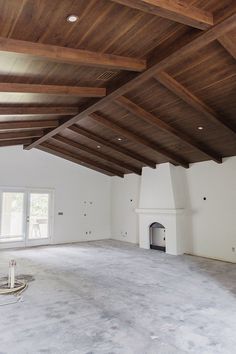 an empty living room with wood beams on the ceiling and fireplace in the center area