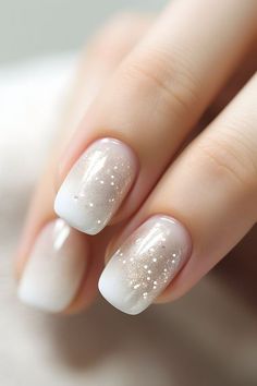 a woman's nails with white and gold glitters