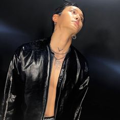 a man wearing a black leather jacket with tattoos on his chest and necklaces around his neck