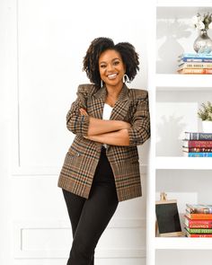 a woman standing in front of a bookshelf with her arms crossed and looking at the camera