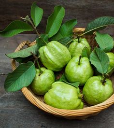 a wicker basket filled with green pears and leaves