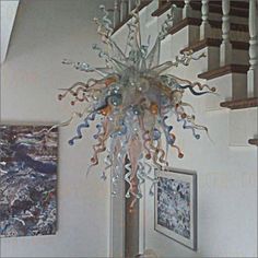 a chandelier hanging from the ceiling in a room with pictures on the wall