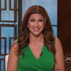 a woman in a green dress is smiling for the camera while sitting down on a white chair