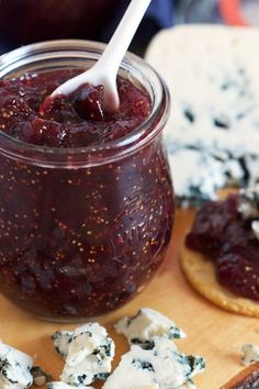 a jar filled with blue cheese and jelly next to crackers on a cutting board