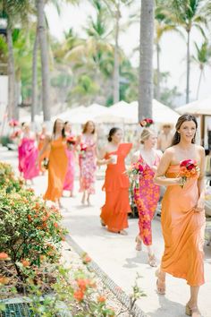 a group of women walking down a sidewalk next to palm trees and umbrellas in the background