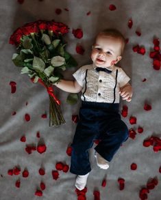 a baby laying down next to a bunch of roses