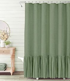 a green shower curtain with ruffles on the bottom, and a mirror in the background