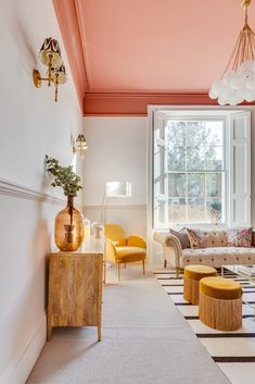 a living room filled with furniture next to a large window covered in pink and white