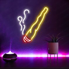 a neon sign that is lit up in the dark, next to a potted plant