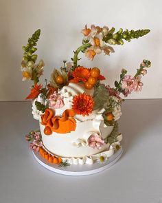 a white cake with orange and pink flowers on it's side, sitting on a table