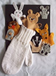 an assortment of stuffed animals and mittens on a white sheet with a black background