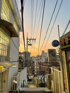 an alley way with cars parked on the side and power lines above it at sunset