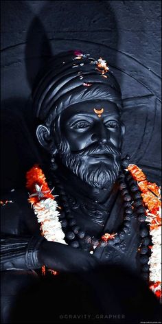 a statue of a man with long hair and beard wearing an orange garland around his neck