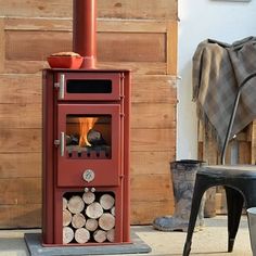 a red stove sitting in the middle of a room next to a chair and table