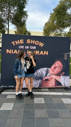 two girls standing in front of a sign with the show live on tour written on it