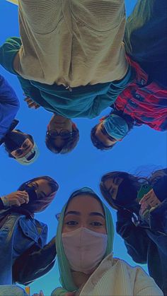 a group of people wearing face masks standing in a circle looking up at the sky