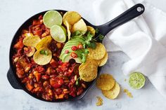 a skillet filled with chili and tortilla chips on top of a white towel