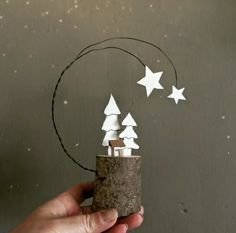 a hand holding a small paper tree with white stars on it and a circle made out of wood